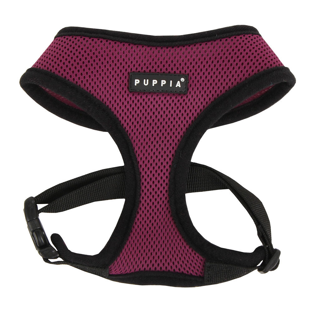 Pink dog harness with black straps on a white background, featuring the Puppia brand.