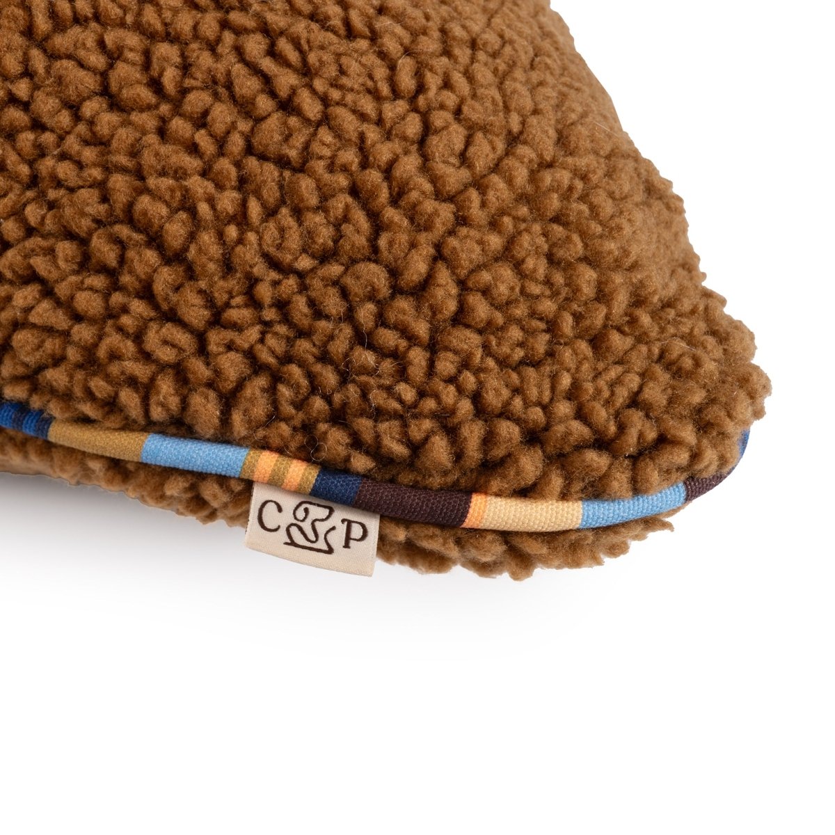 Brand Stripe Sherpa Pillow | Rust, close-up of sherpa and stripe cording